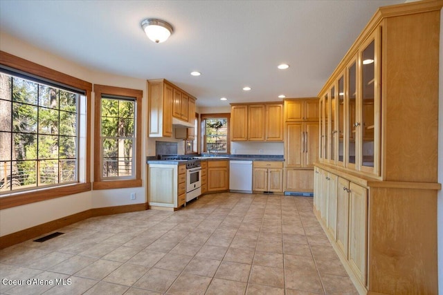 kitchen featuring visible vents, under cabinet range hood, stainless steel stove, dishwasher, and baseboards
