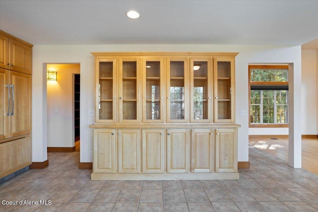 kitchen with light tile patterned floors, baseboards, glass insert cabinets, and recessed lighting