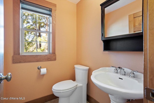 bathroom with toilet, a sink, and baseboards