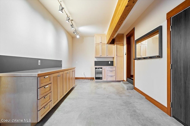 kitchen featuring concrete floors, baseboards, light brown cabinetry, wine cooler, and rail lighting