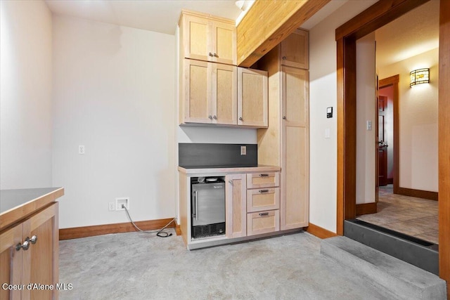 kitchen featuring light carpet, baseboards, and light brown cabinetry