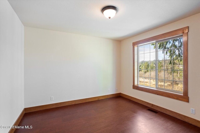 spare room with wood finished floors, baseboards, and visible vents