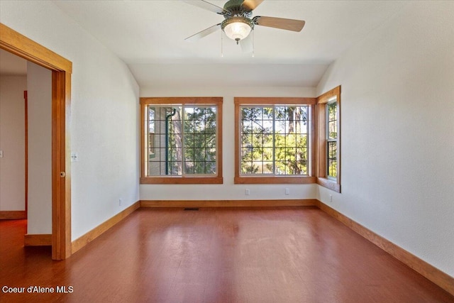 empty room with wood finished floors, ceiling fan, baseboards, and lofted ceiling