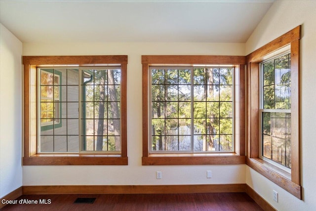 interior space with wood finished floors, baseboards, lofted ceiling, and visible vents