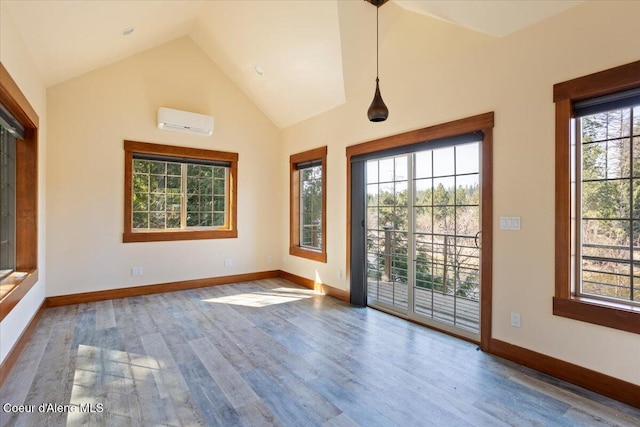 spare room with high vaulted ceiling, an AC wall unit, baseboards, and wood finished floors