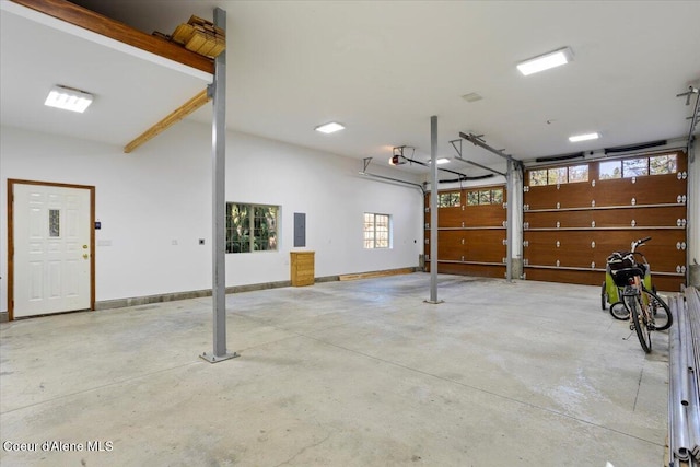 garage featuring a garage door opener, baseboards, and electric panel