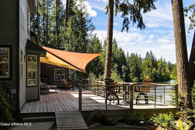 deck with a water view and outdoor dining space