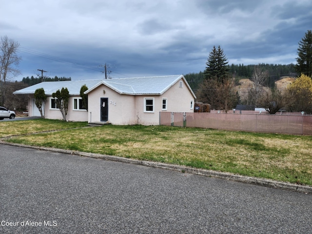 216 W Oak Ave, Osburn, ID 83849 - view of front of house featuring stucco siding, an attached garage, a front lawn, metal roof, and fence