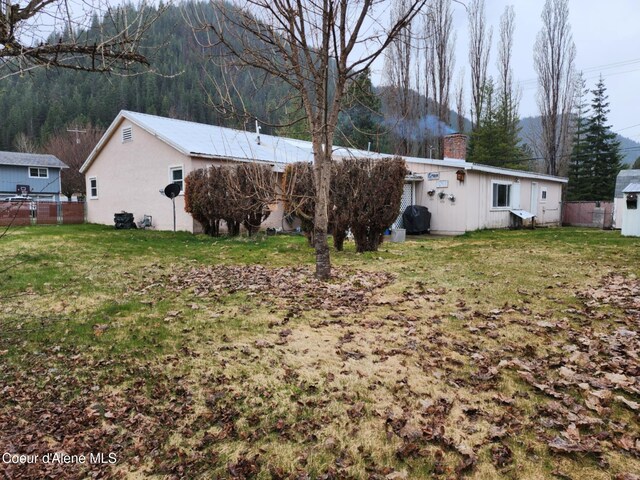 216 W Oak Ave, Osburn, ID 83849 - rear view of house with fence, a lawn, and a chimney