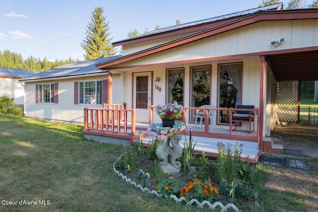 view of front of property featuring a front lawn, metal roof, and covered porch