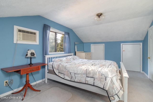 bedroom featuring lofted ceiling, a textured ceiling, carpet, a wall mounted AC, and baseboards
