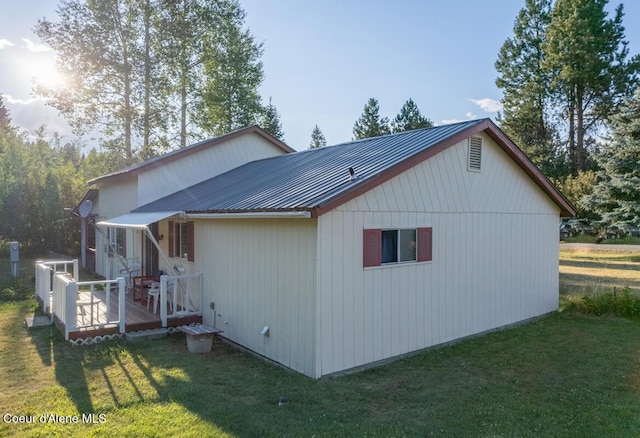 view of property exterior with a yard, metal roof, and a wooden deck