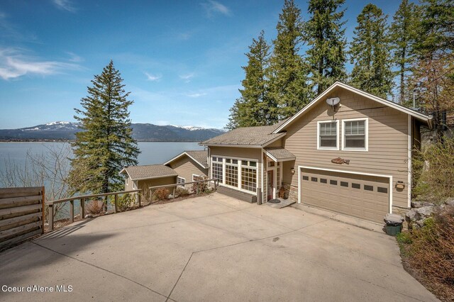 3765 Bottle Bay Rd, Sagle, ID 83860 - view of front of home with fence, a water and mountain view, a garage, and concrete driveway
