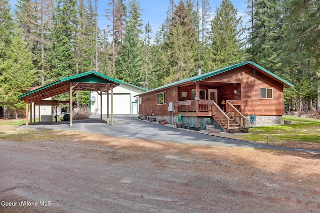 view of front of property with covered porch, a detached carport, stairway, an outdoor structure, and aphalt driveway