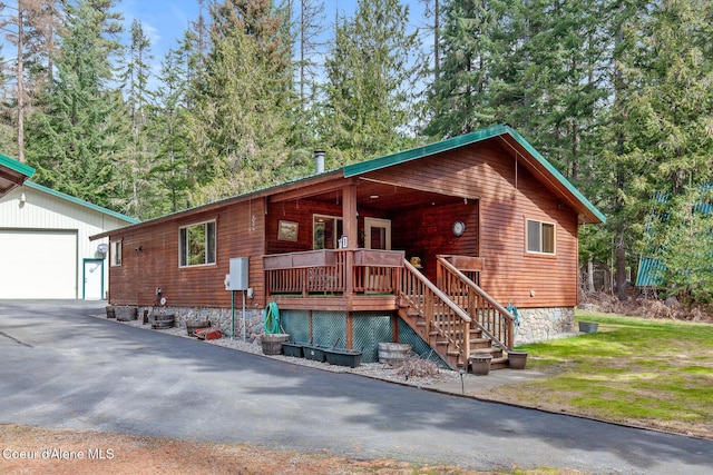 rustic home featuring covered porch, an outbuilding, driveway, and stairway