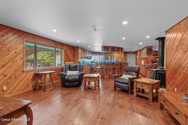 living area with recessed lighting, a wood stove, wood walls, and light wood-style flooring