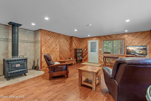 living area featuring recessed lighting, a wood stove, wood walls, and light wood-style flooring