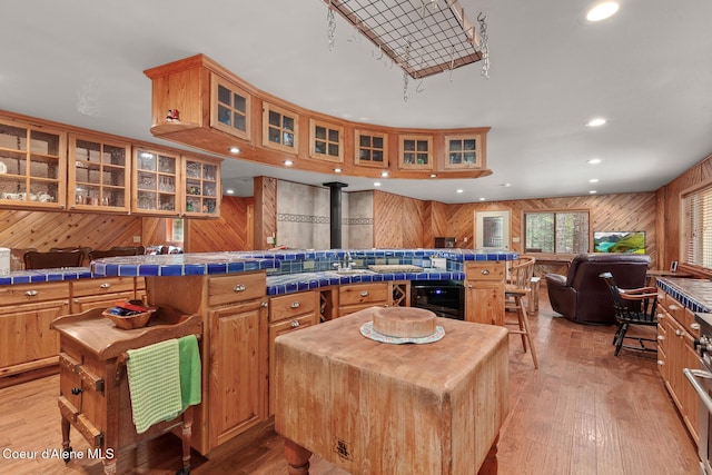 kitchen with a kitchen island, a wood stove, light wood-type flooring, wood walls, and open floor plan