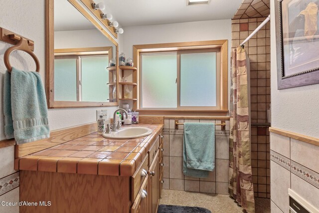 bathroom featuring a shower with curtain, tile walls, visible vents, and vanity