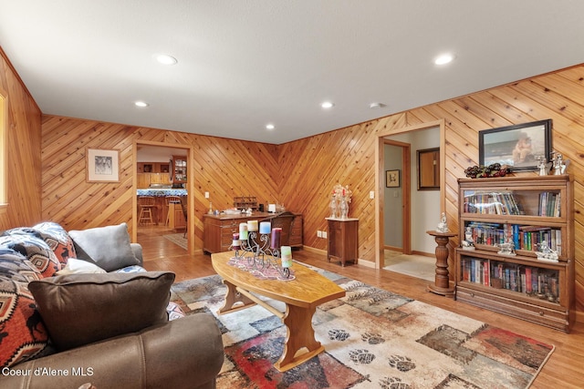 living room featuring recessed lighting, baseboards, wood walls, and wood finished floors