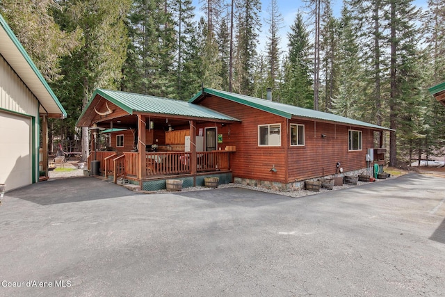 chalet / cabin with a porch, metal roof, and aphalt driveway