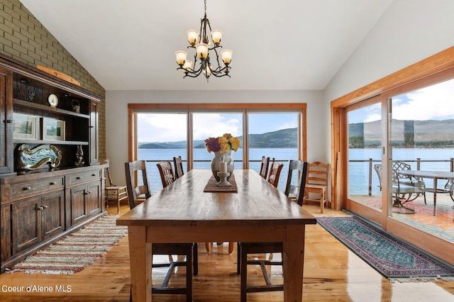 dining area with a chandelier, a water view, lofted ceiling, and a wealth of natural light