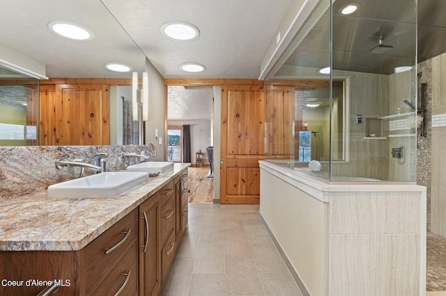 full bath featuring double vanity, a sink, and a stall shower