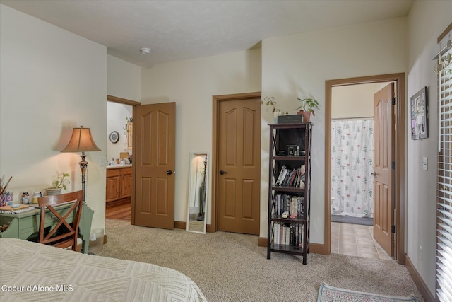 bedroom featuring light colored carpet, connected bathroom, and baseboards