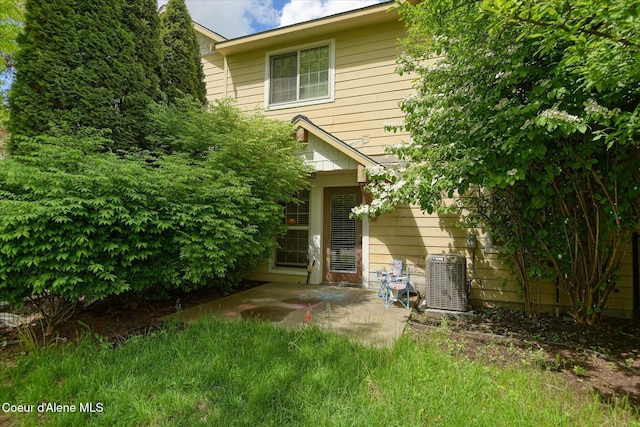 back of property with central AC unit and a patio