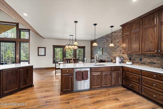kitchen with dishwasher, a sink, light countertops, a peninsula, and light wood finished floors