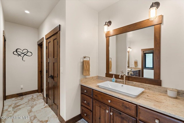 bathroom featuring baseboards, marble finish floor, and vanity
