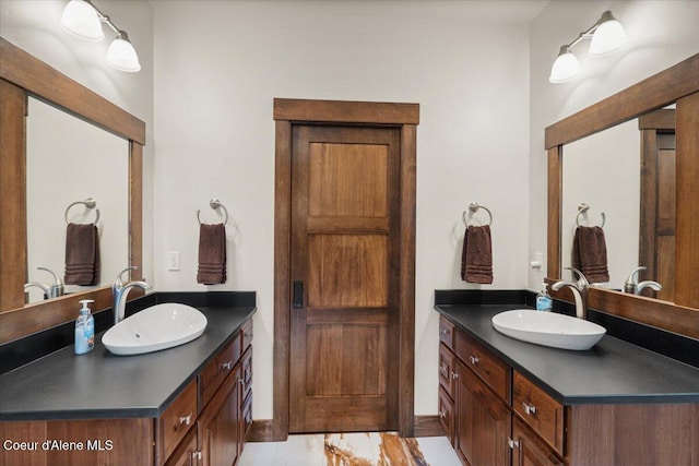full bathroom featuring two vanities, marble finish floor, and a sink