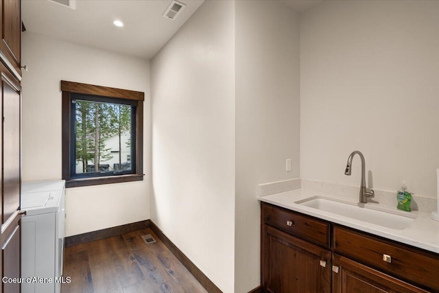 interior space featuring dark wood finished floors, visible vents, a sink, baseboards, and cabinet space