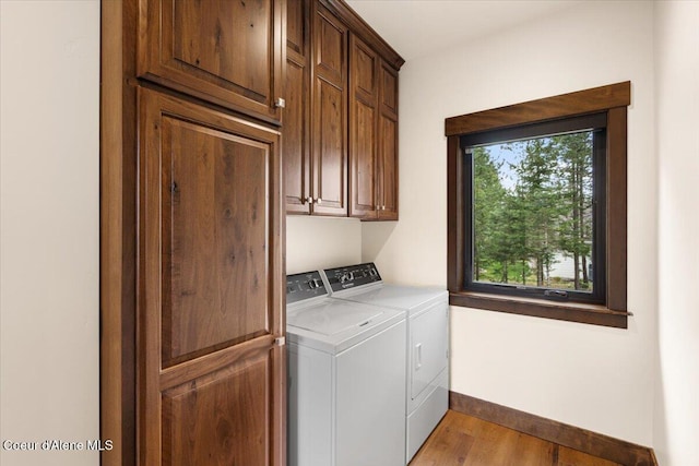laundry room with wood finished floors, baseboards, cabinet space, and washer and clothes dryer