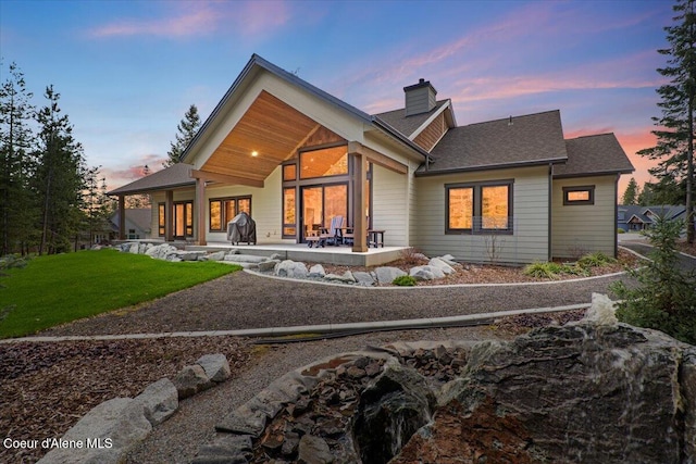back of house featuring a patio, a chimney, and a yard