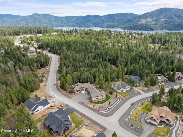drone / aerial view with a forest view and a water and mountain view
