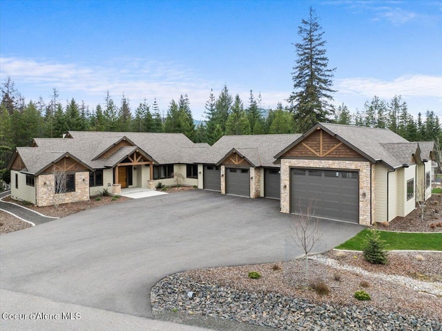 view of front of home featuring a shingled roof, a garage, stone siding, and driveway