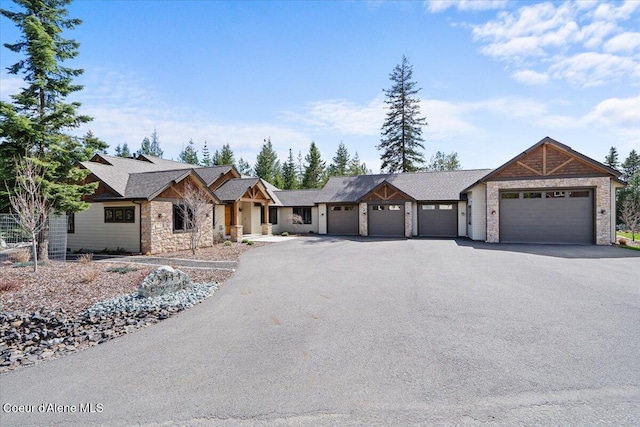 view of front facade featuring a shingled roof, aphalt driveway, a garage, and stone siding