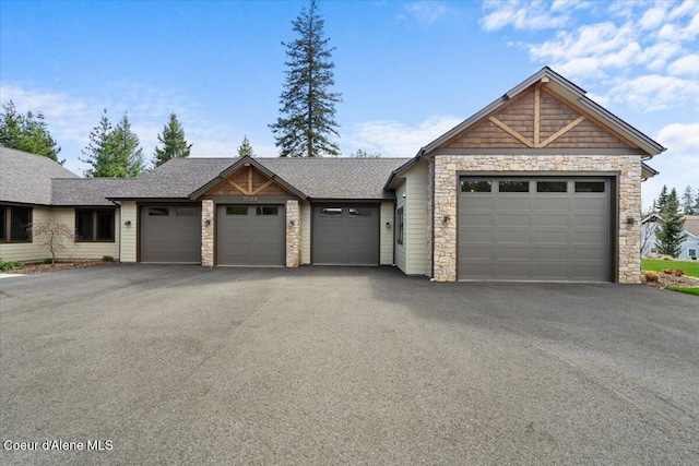 view of front of property with a shingled roof, driveway, stone siding, and an attached garage