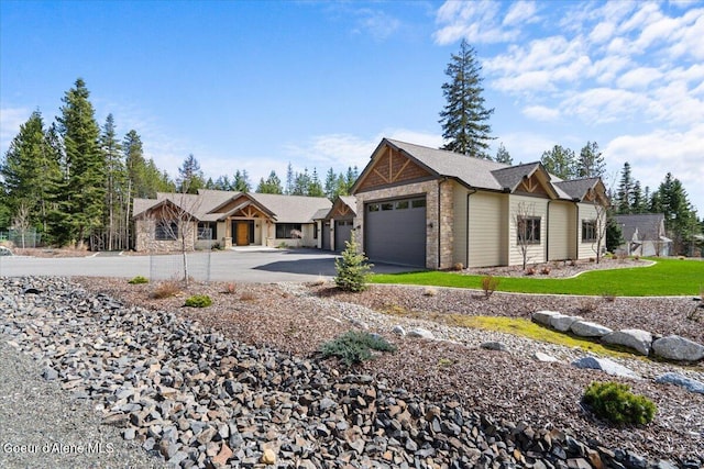 view of front of property featuring aphalt driveway, stone siding, and an attached garage