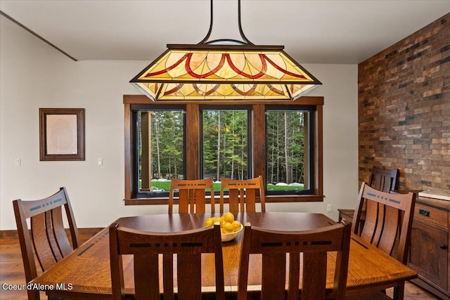 dining area with brick wall and wood finished floors