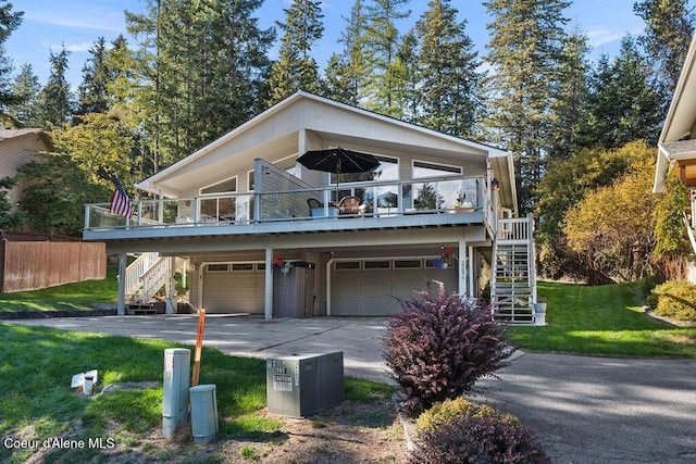 view of front of property featuring a front yard, an attached garage, concrete driveway, and stairs