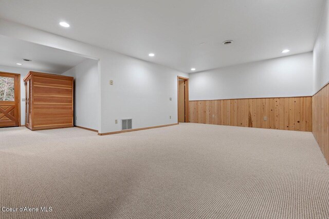 below grade area with wooden walls, a wainscoted wall, visible vents, and carpet floors