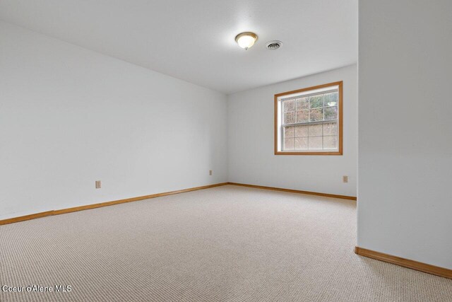 unfurnished room with baseboards, visible vents, and light carpet