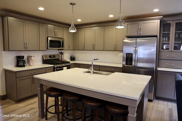 kitchen with stainless steel appliances, a breakfast bar area, light wood-type flooring, and a sink