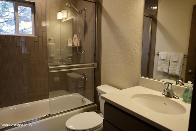 bathroom with toilet, a textured wall, combined bath / shower with glass door, and vanity