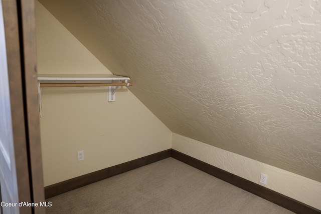 walk in closet with carpet and vaulted ceiling