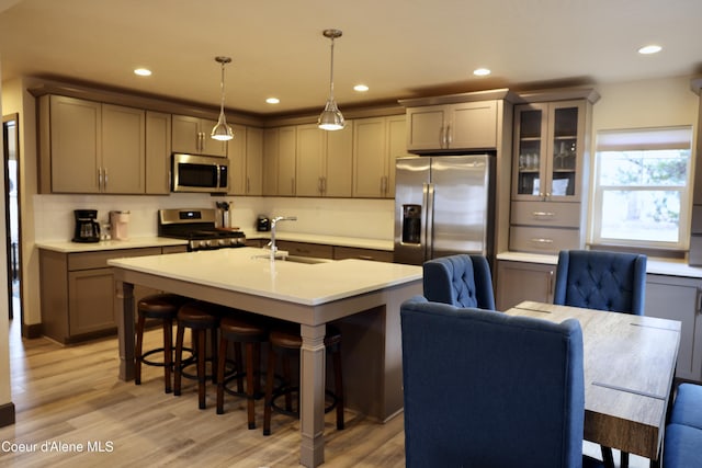 kitchen with a breakfast bar area, light wood finished floors, a sink, and appliances with stainless steel finishes
