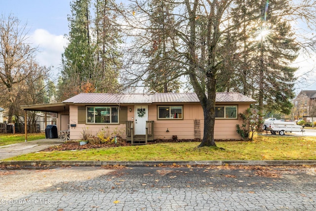 ranch-style house featuring a front yard, a carport, metal roof, and driveway