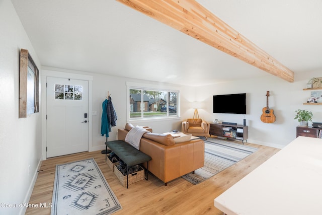 living area featuring beam ceiling, baseboards, and light wood-style floors